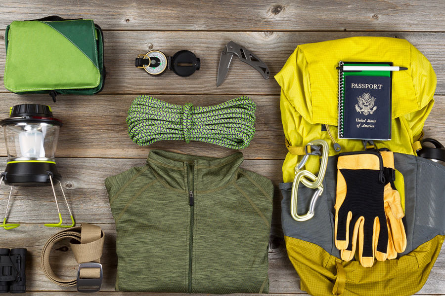 High angled view of organized hiking gear for climbing placed on rustic wooden boards.