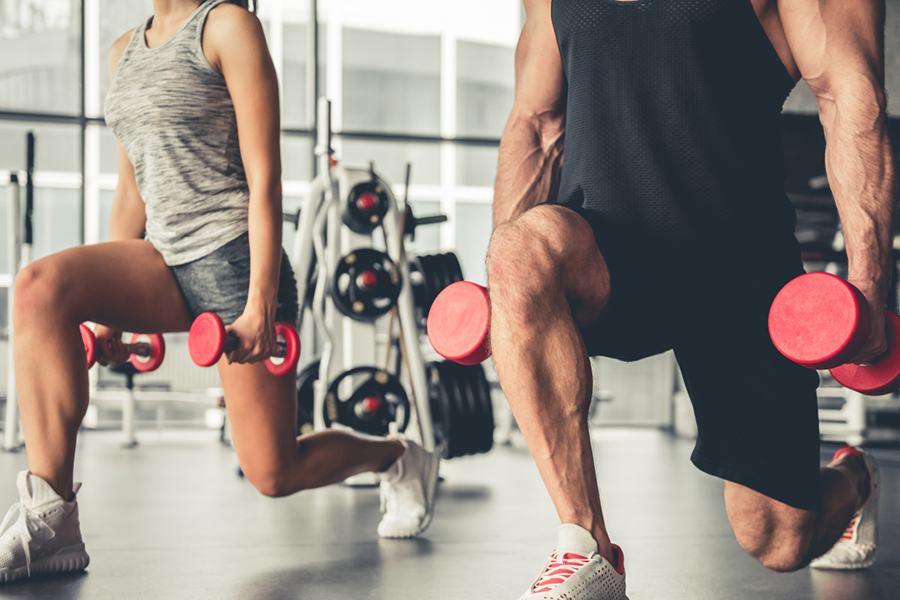 Attractive sports people are working out with dumbbells in gym